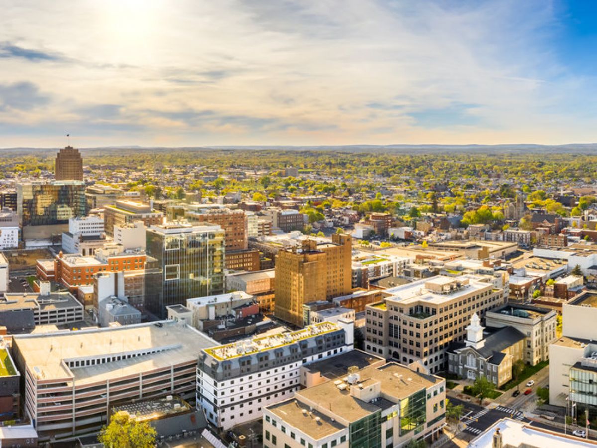 Aerial view of a cityscape with modern buildings under a bright, sunny sky.