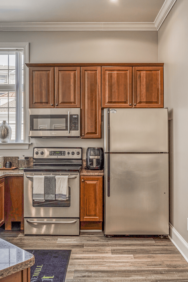 Modern kitchen with wooden cabinets, stainless steel appliances, and large windows letting in natural light.